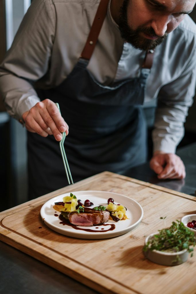 Expert de Station Gourmet dressant une assiette avec précision pour un service de haute qualité.