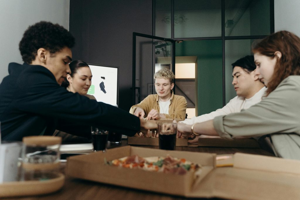 Équipe de collègues dégustant un dîner pizza dans un bureau moderne.